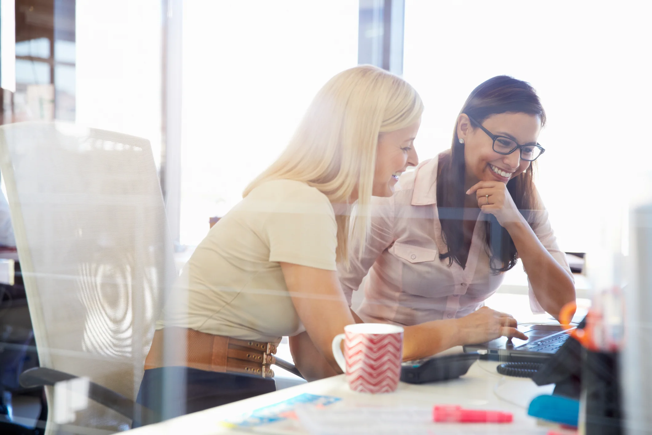 Schmuckbild, zwei Frauen im Büro arbeiten nebeneinander am Schreibtisch