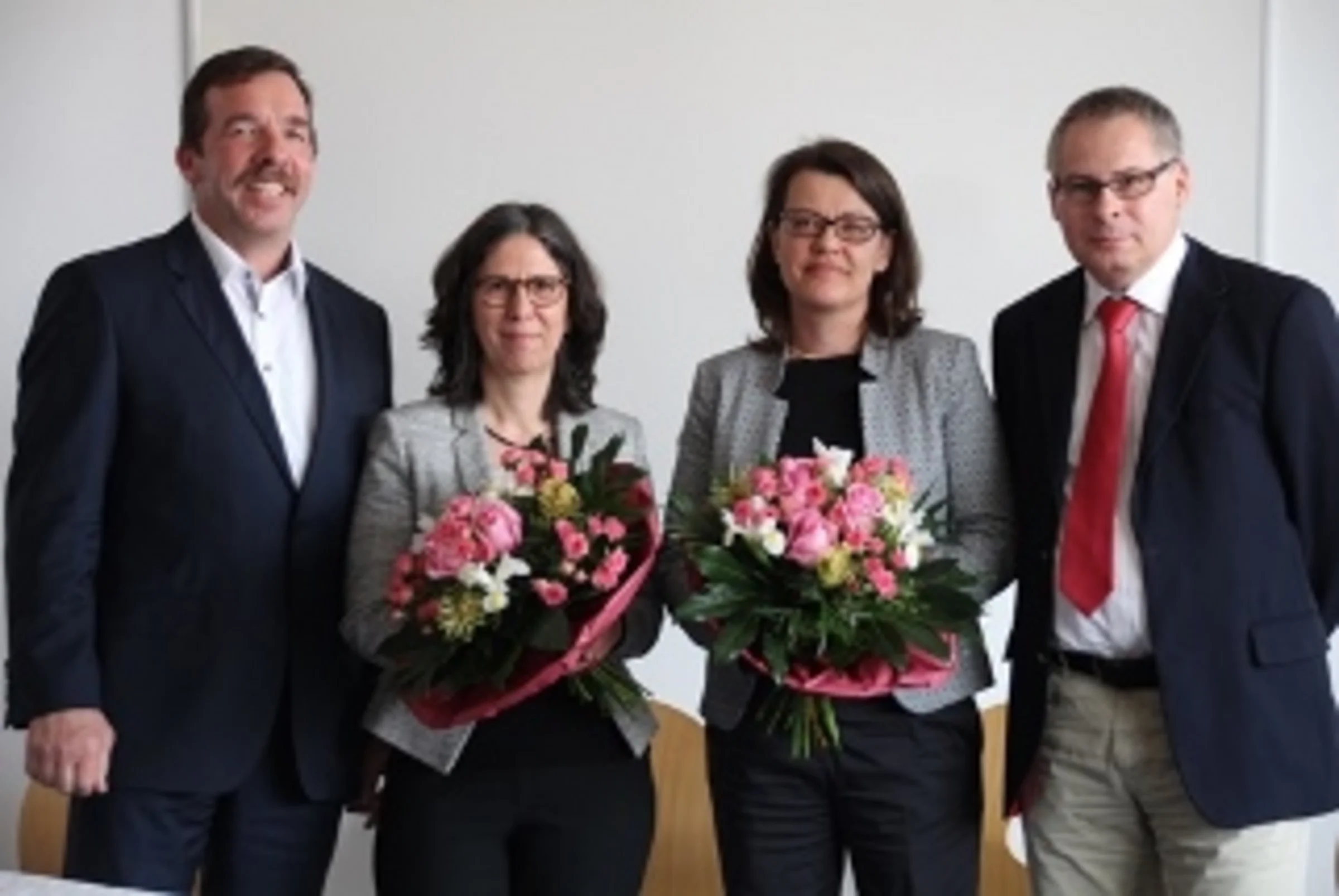 Schmuckbild Susanne Kretschmer und Dr. Iris Pfeiffer haben Blumensträuße in der Hand und stehen zwischen zwei Männdern