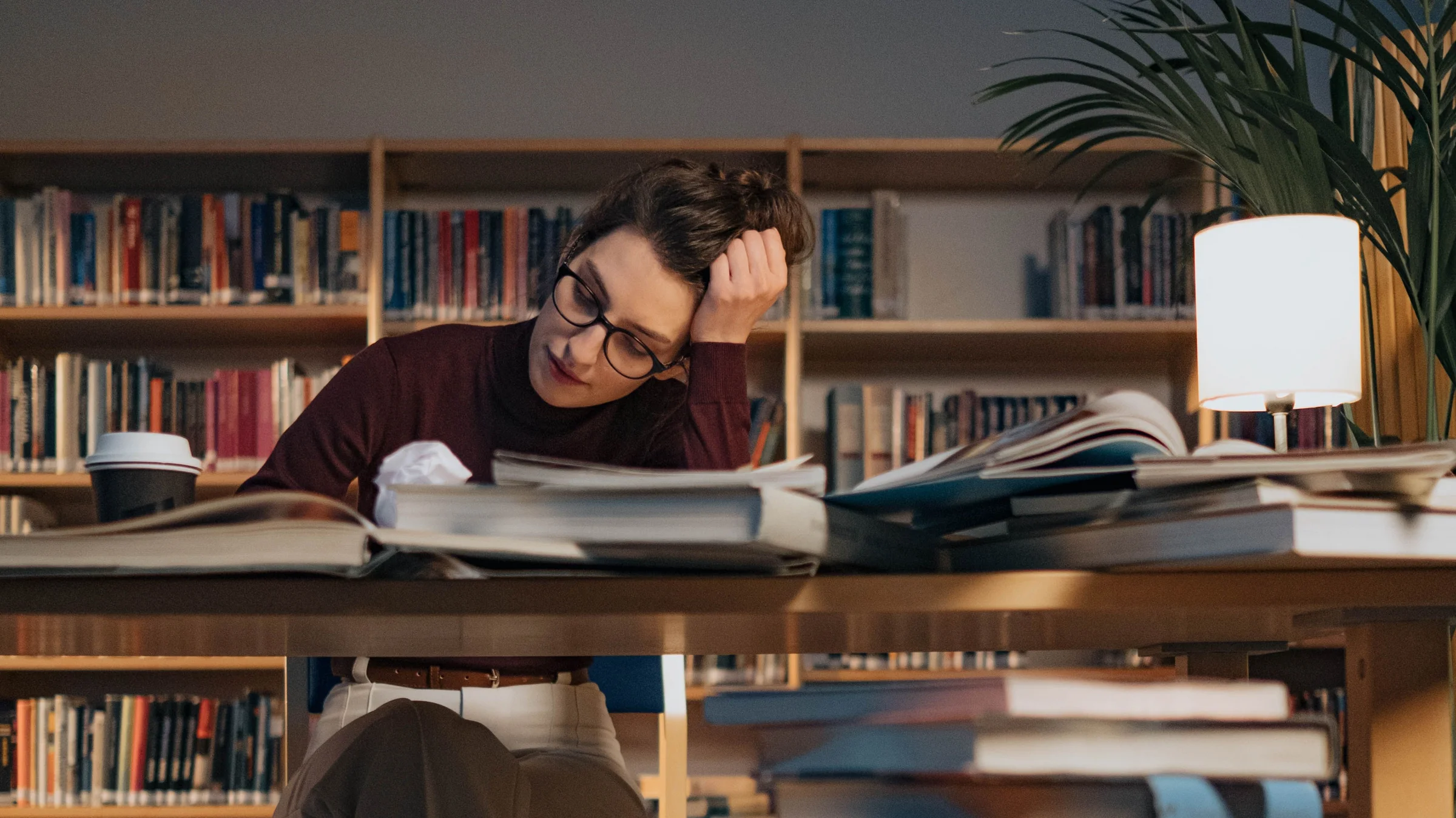 Schmuckbild Frau am Schreibtisch mit Büchern und Unterlagen.